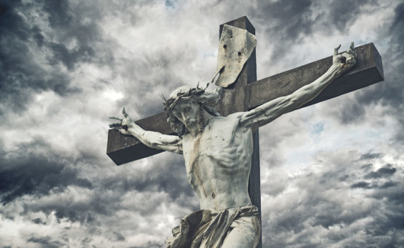 Crucifixion. Christian cross with Jesus Christ statue over stormy clouds. religion and spirituality concept.